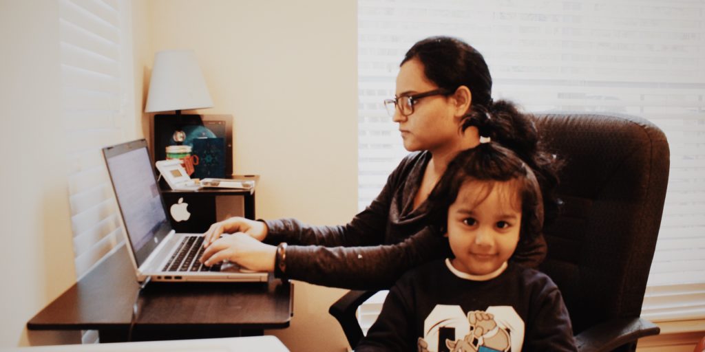 Busy mom working at desk with young daughter