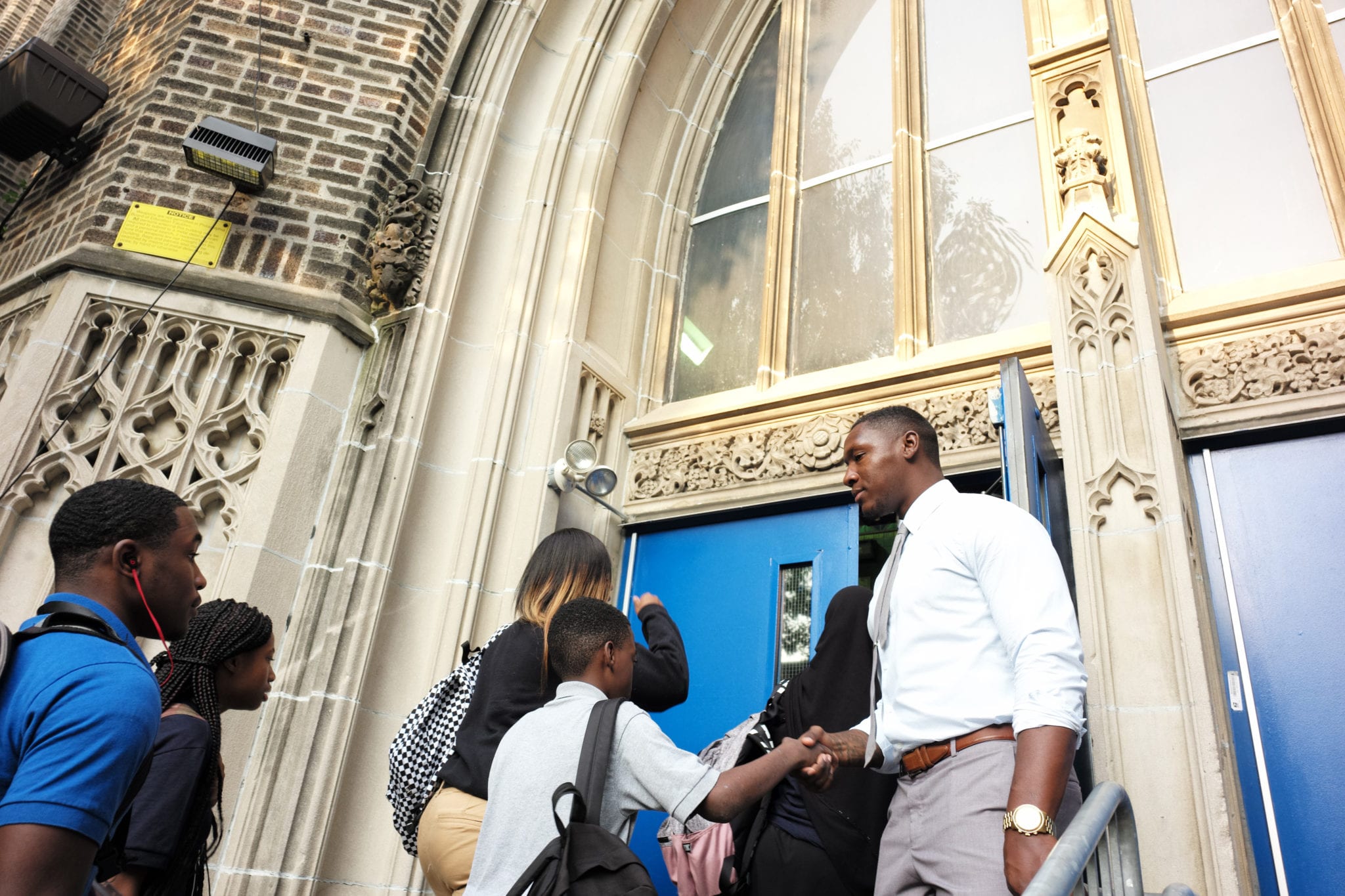 Teacher Greeting Students Outside Schoo